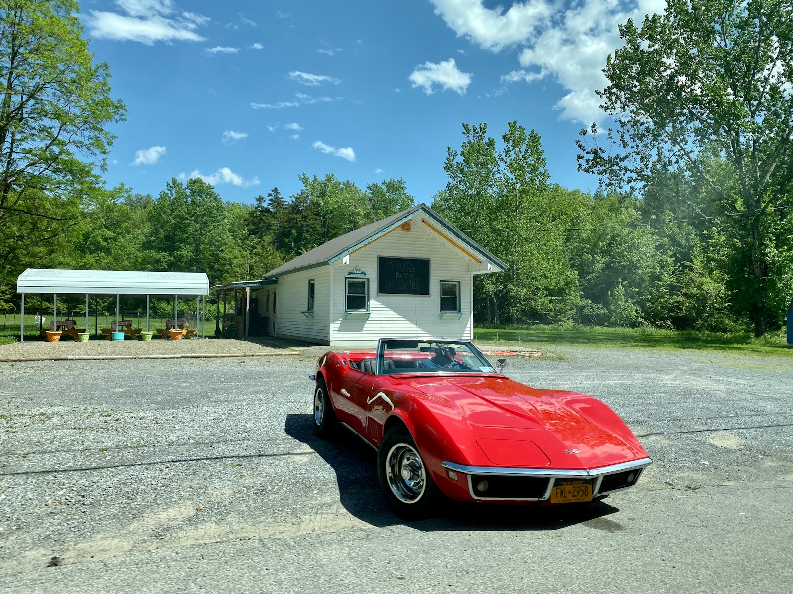 red car parked in front of white and brown house